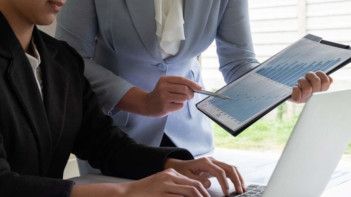 Two business leader women discussing the charts and graphs showing the results.