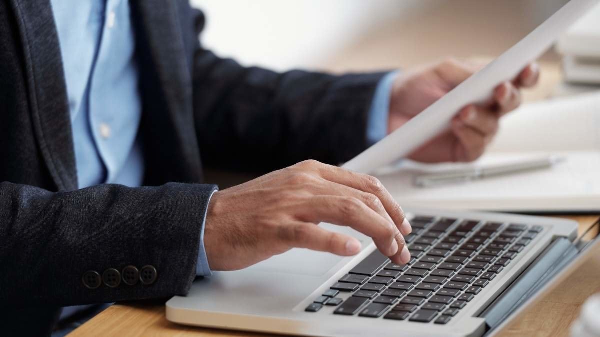 Hands of businessman checking document and typing on keyboard