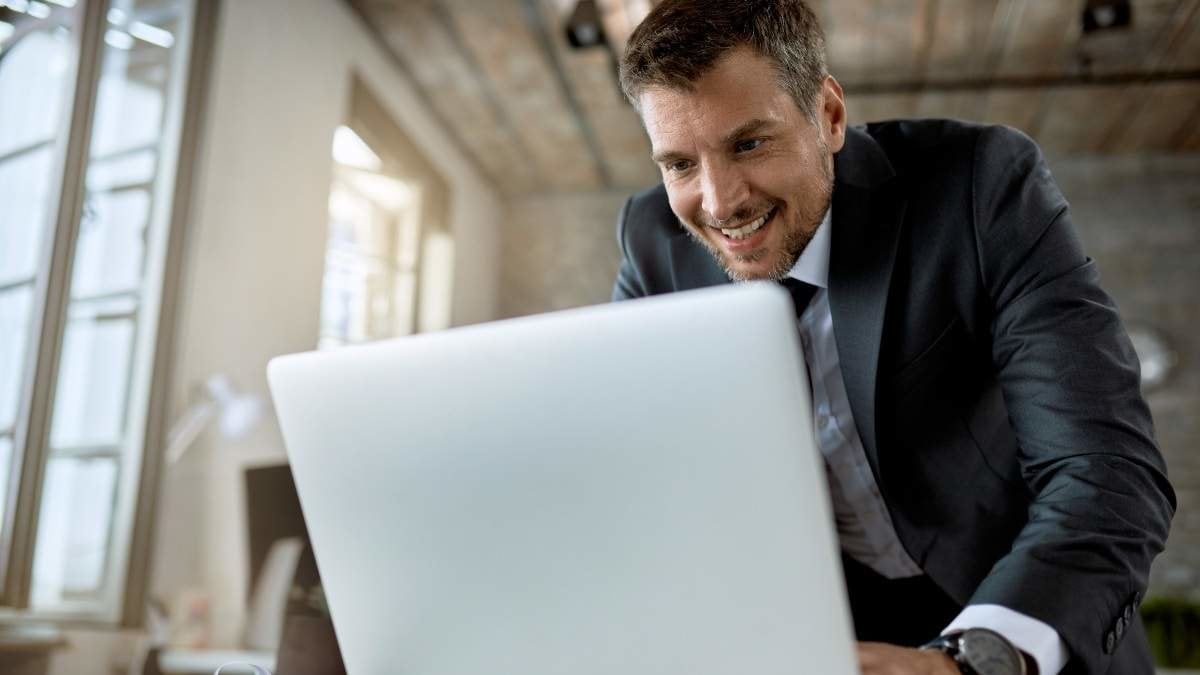 Happy entrepreneur typing an e-mail while working on laptop in the office.