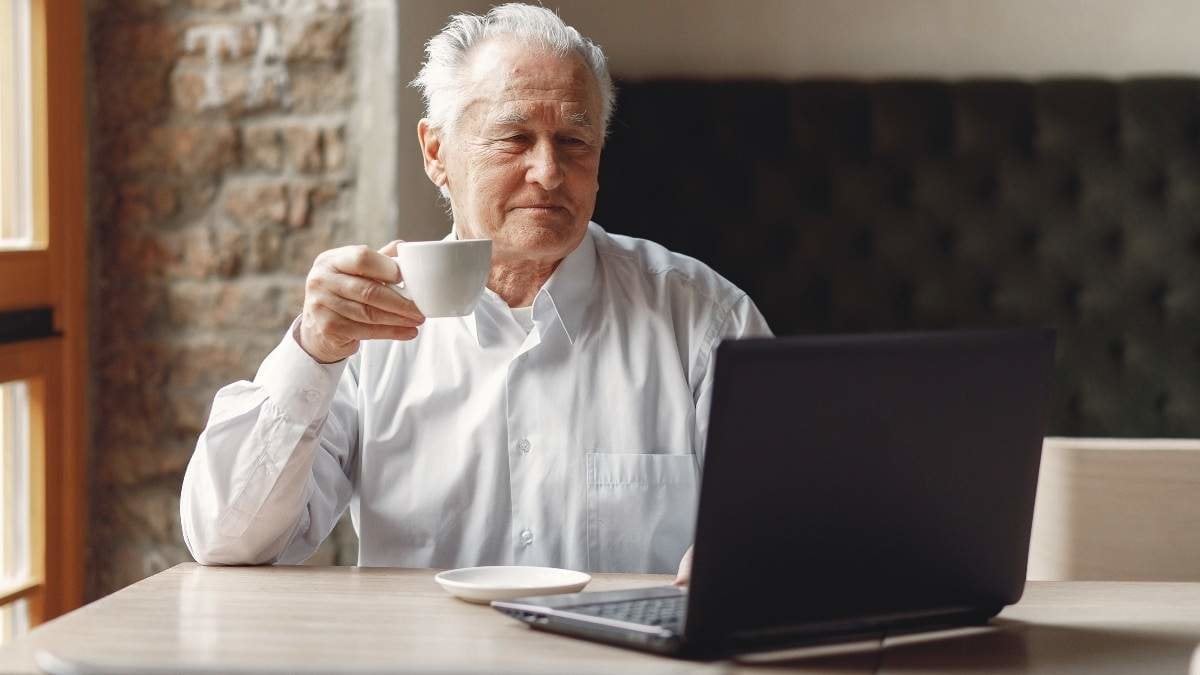 Senior with a laptop. Businessman working in the cafe. Man in a white shirt.