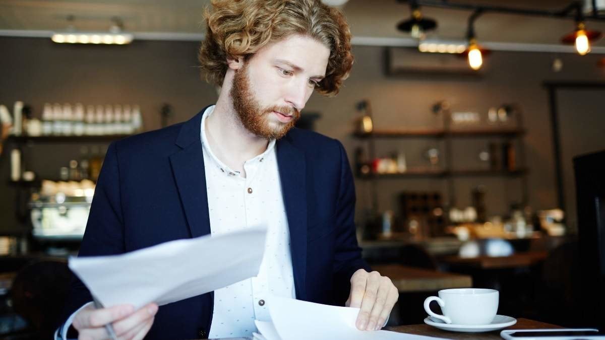 Young confident businessman concentrating on paperwork by cup of coffee