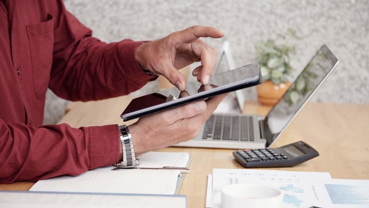 Close-up of businessman sitting at office desk and using digital tablet for work