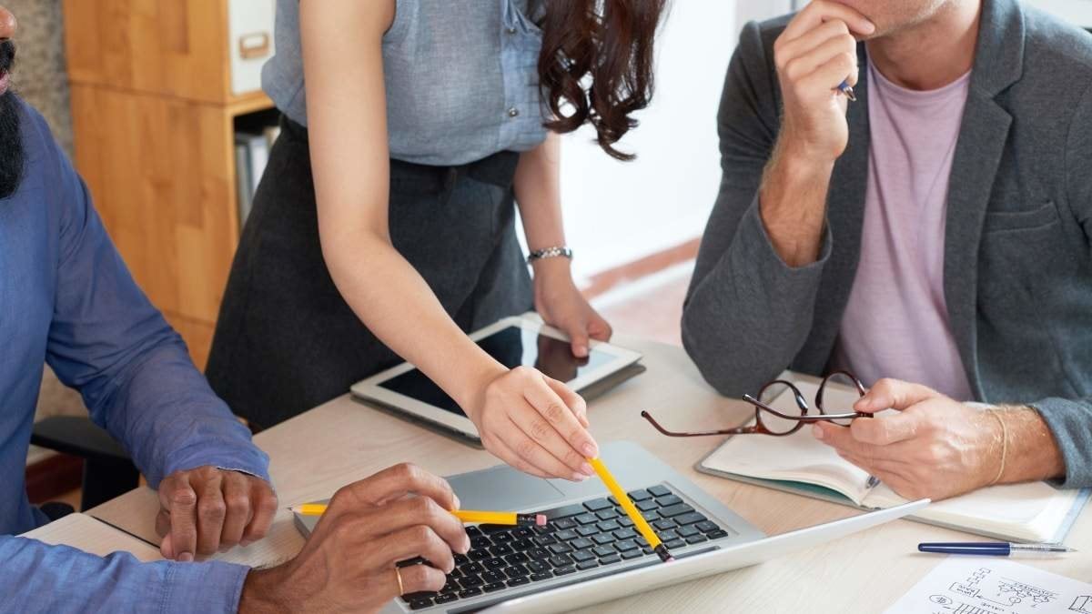 Businesswoman presenting something to her team on laptop during meeting