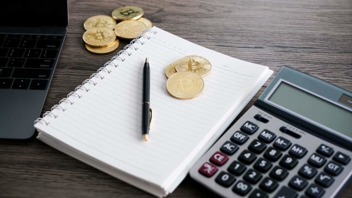 Laptop with calculator and golden bitcoin. Cryptocurrency investors concept.