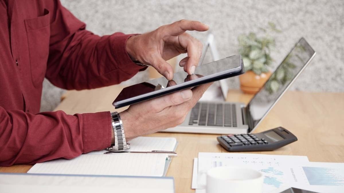 Close-up of businessman sitting at office desk and using digital tablet for work