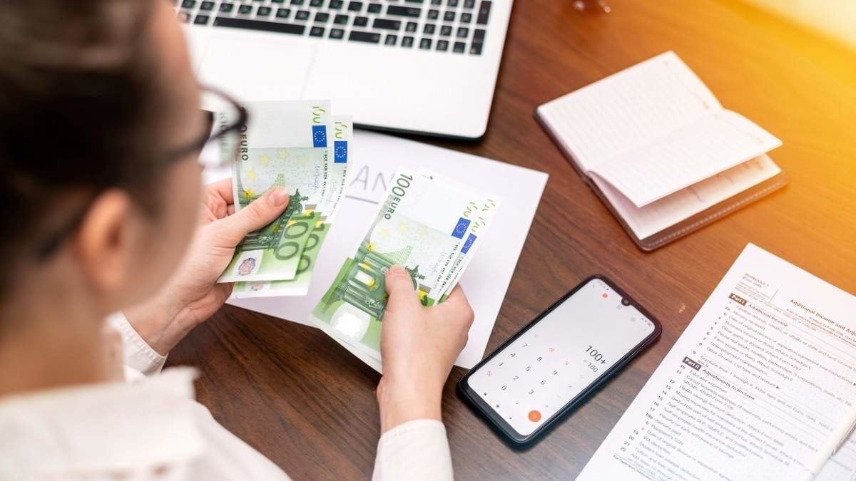 Woman working with finances counting money on the table. Smertphone, notepad